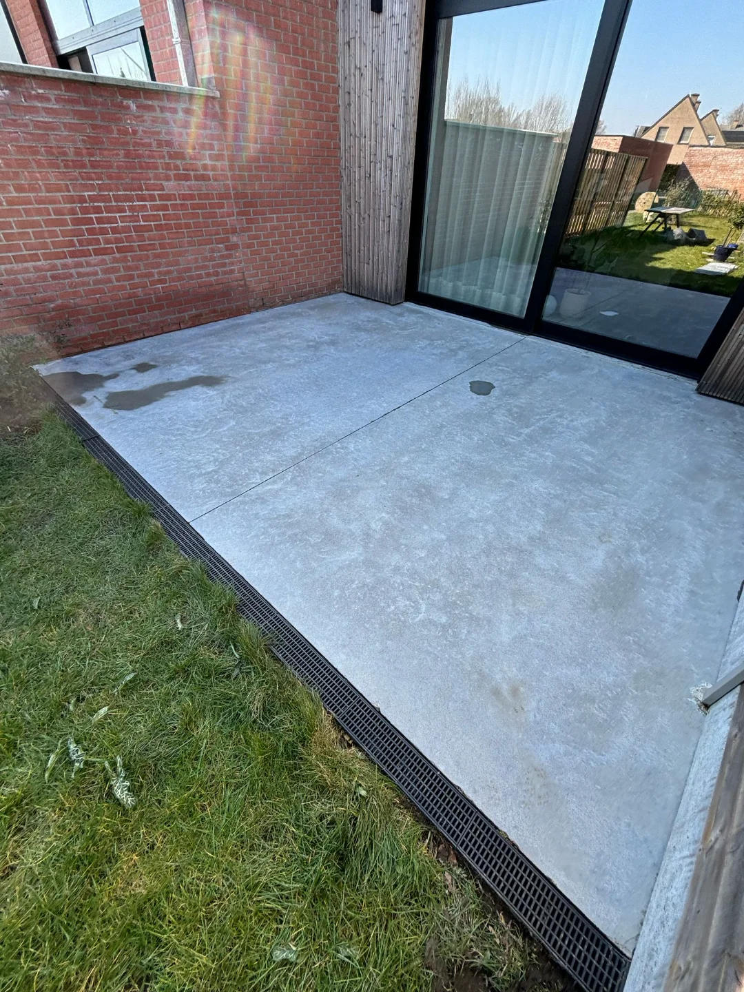 Betonnen terras reinigen: mos en aanslag weg met Renovivo Fris gereinigd betonnen terras met drainagegoot, vrij van mos en aanslag, door Renovivo in West- of Oost-Vlaanderen.