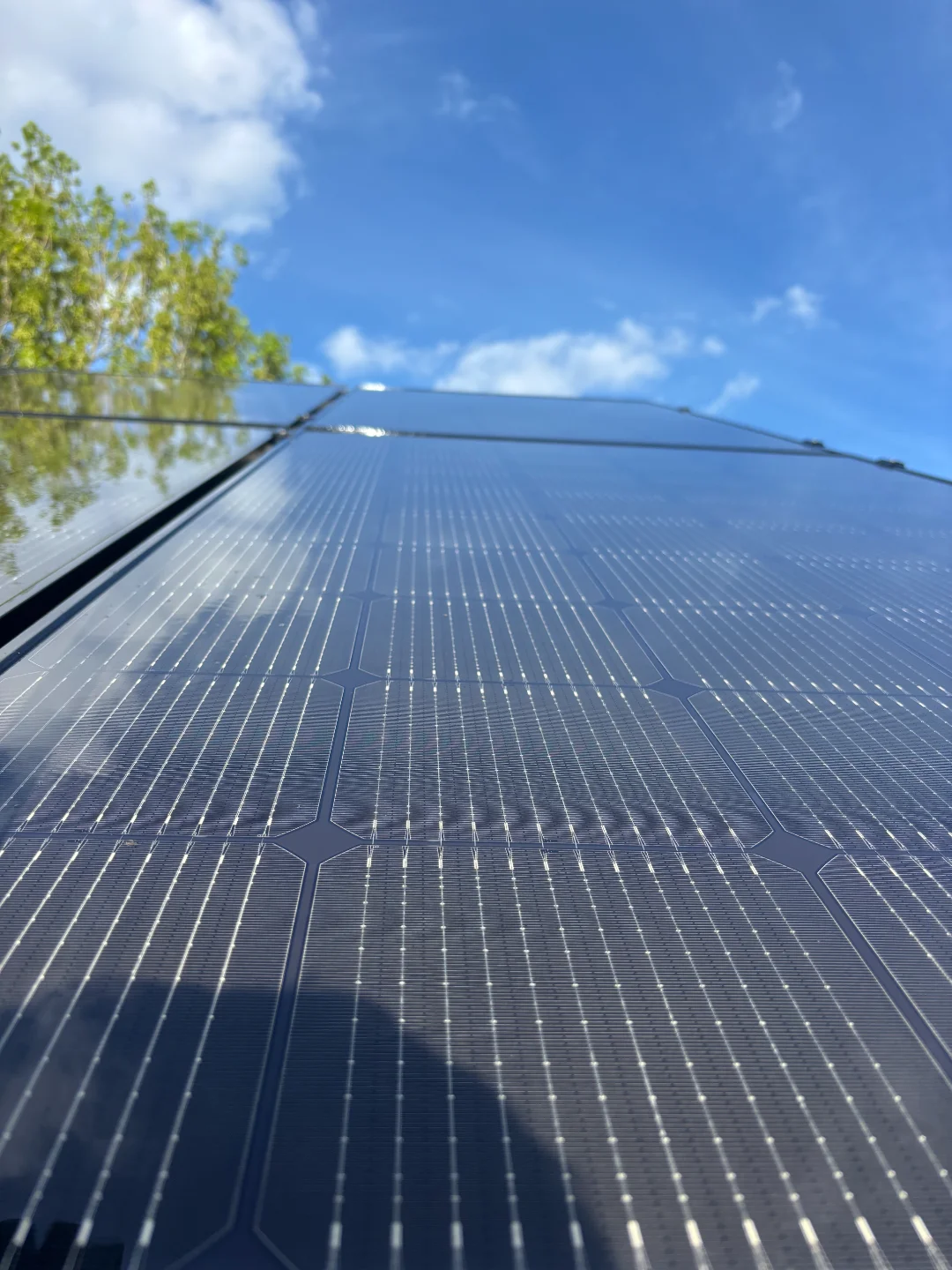 Close-up van schone zonnepanelen op een dak onder een blauwe lucht, gereinigd door Renovivo voor optimaal rendement.