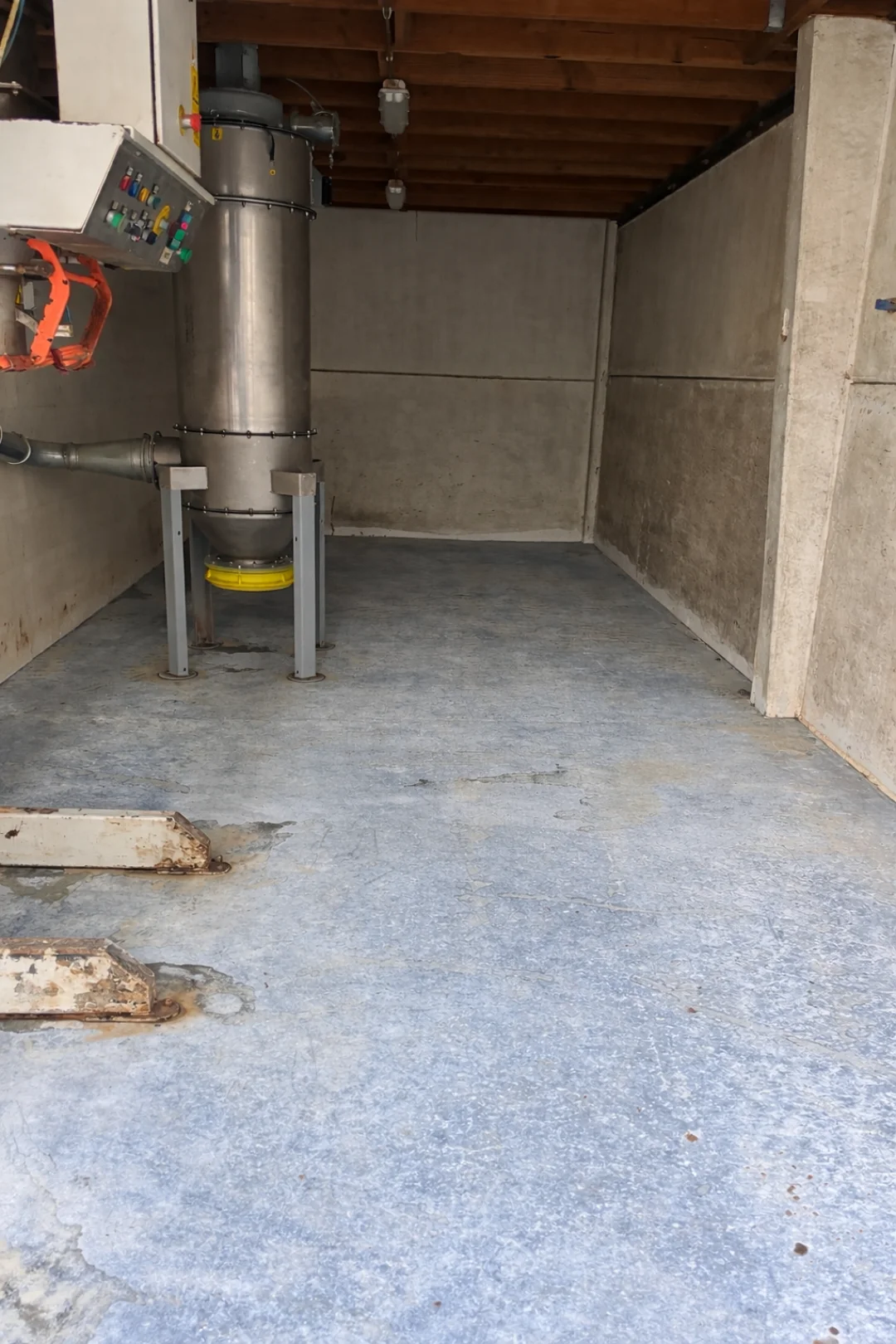 Betonvloer en muren in een industriële bedrijfsruimte met machines. Renovivo biedt professionele reiniging voor grote oppervlakken en zakelijke locaties.
