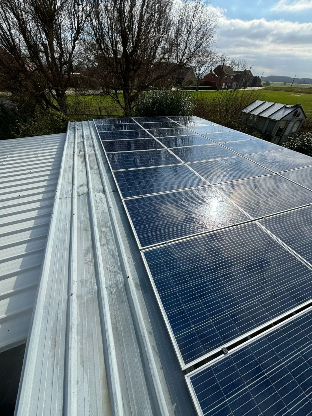 Propere zonnepanelen op een rood dak na professionele reiniging door Renovivo voor optimaal rendement in Vlaanderen.